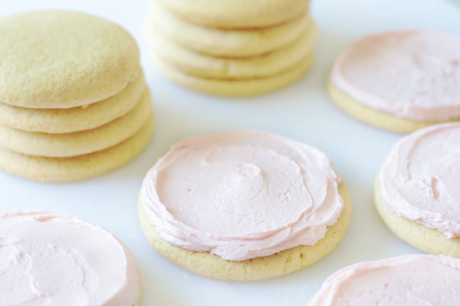 stack of unfrosted sugar cookies next to pink frosted buttermilk sugar cookies
