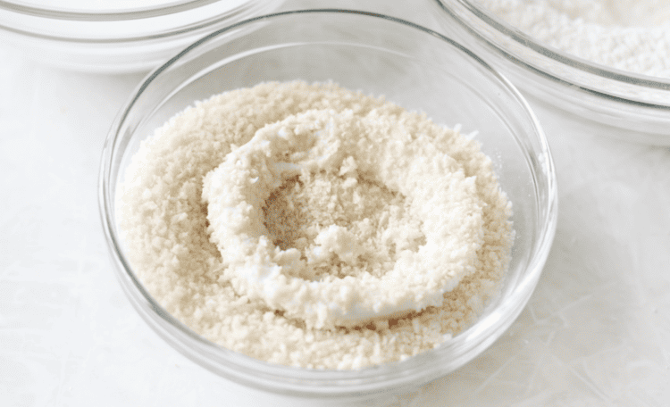 Bowl of panko crumbs and onion ring dipped in them.