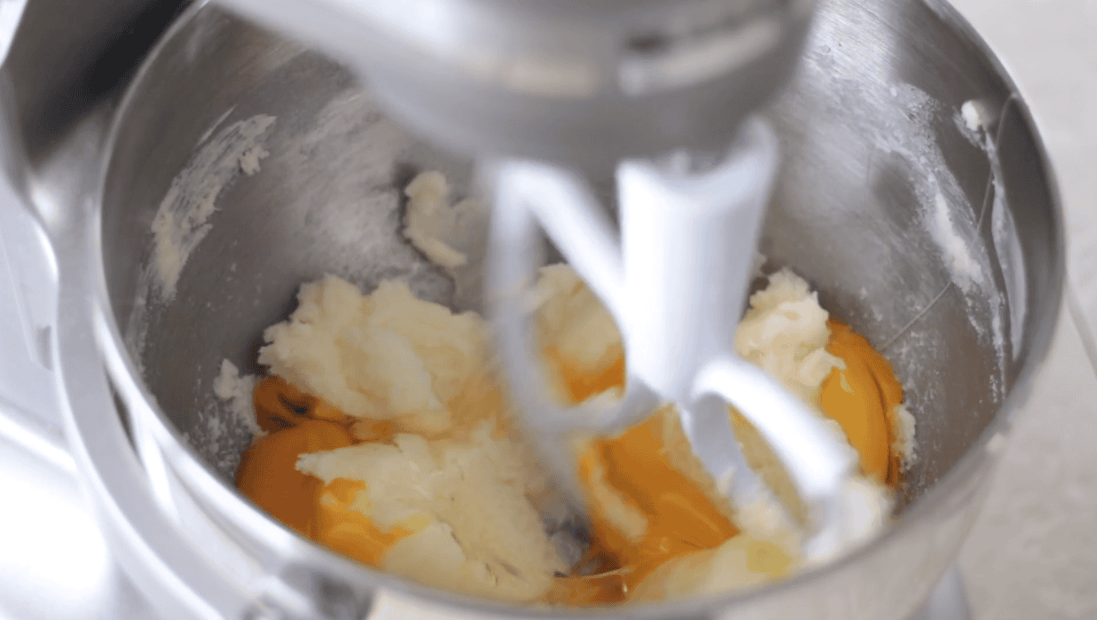 Mixer creaming sugar, butter and eggs in stand mixer.