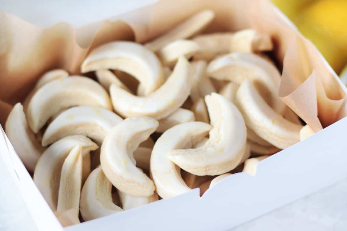 white cookie box with parchment paper inside and lemon cookies.