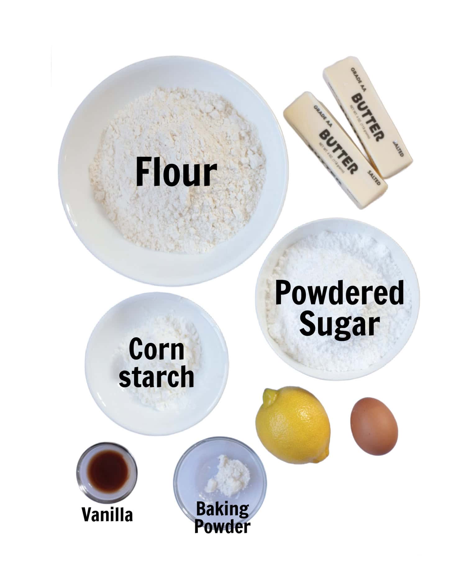 Bowl of flour, powdered sugar, corn starch and baking powder with two sticks of butter, one lemon, an egg and a small bowl of vanilla.