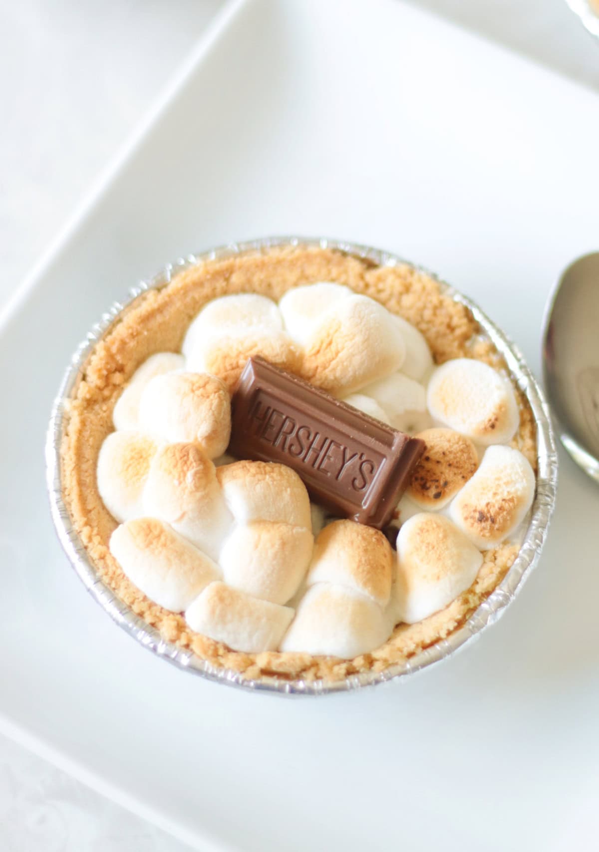 mini s'mores pie on white plate and spoon next to it.