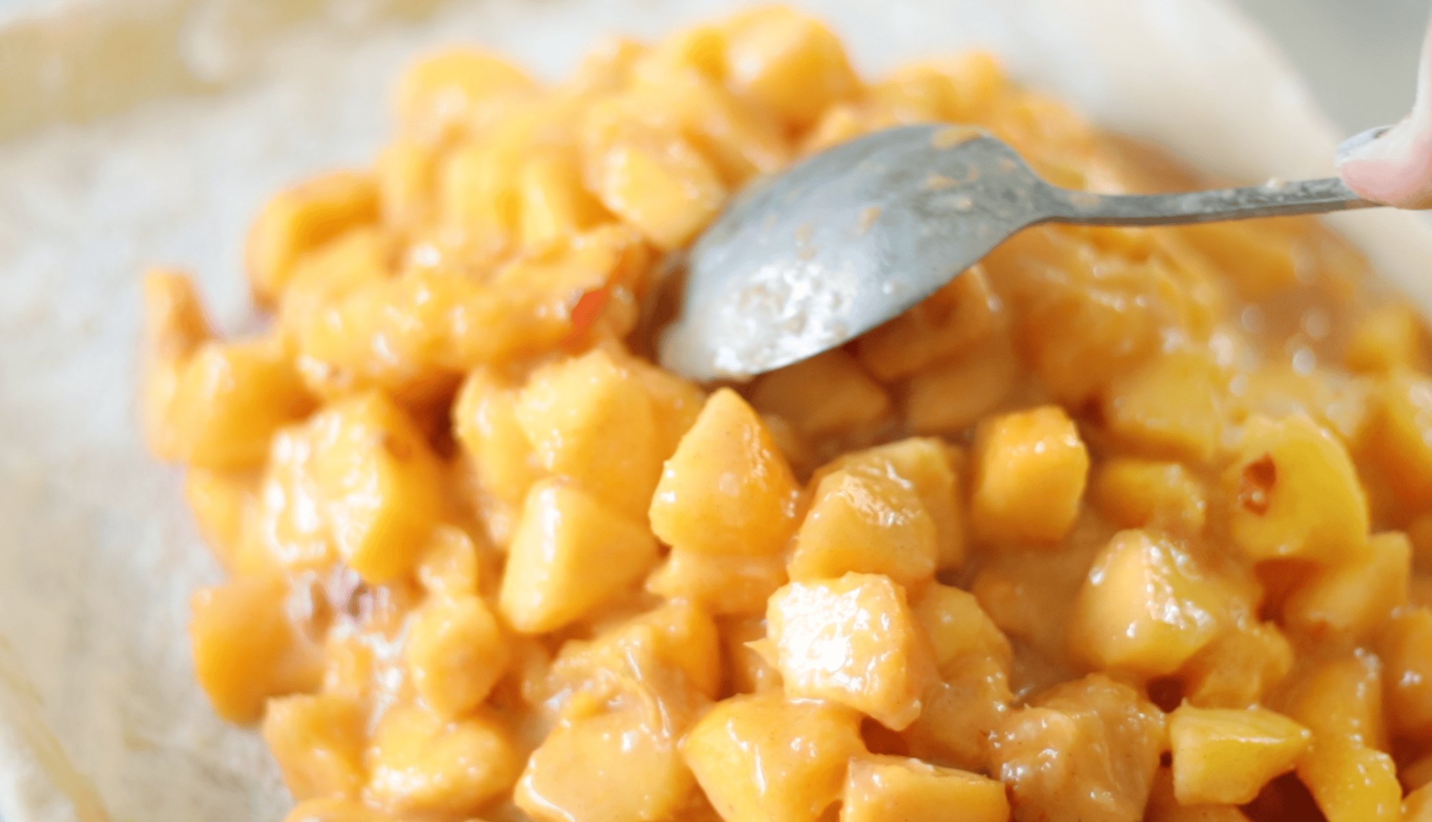 Peach pie filling spooned onto pie crust.