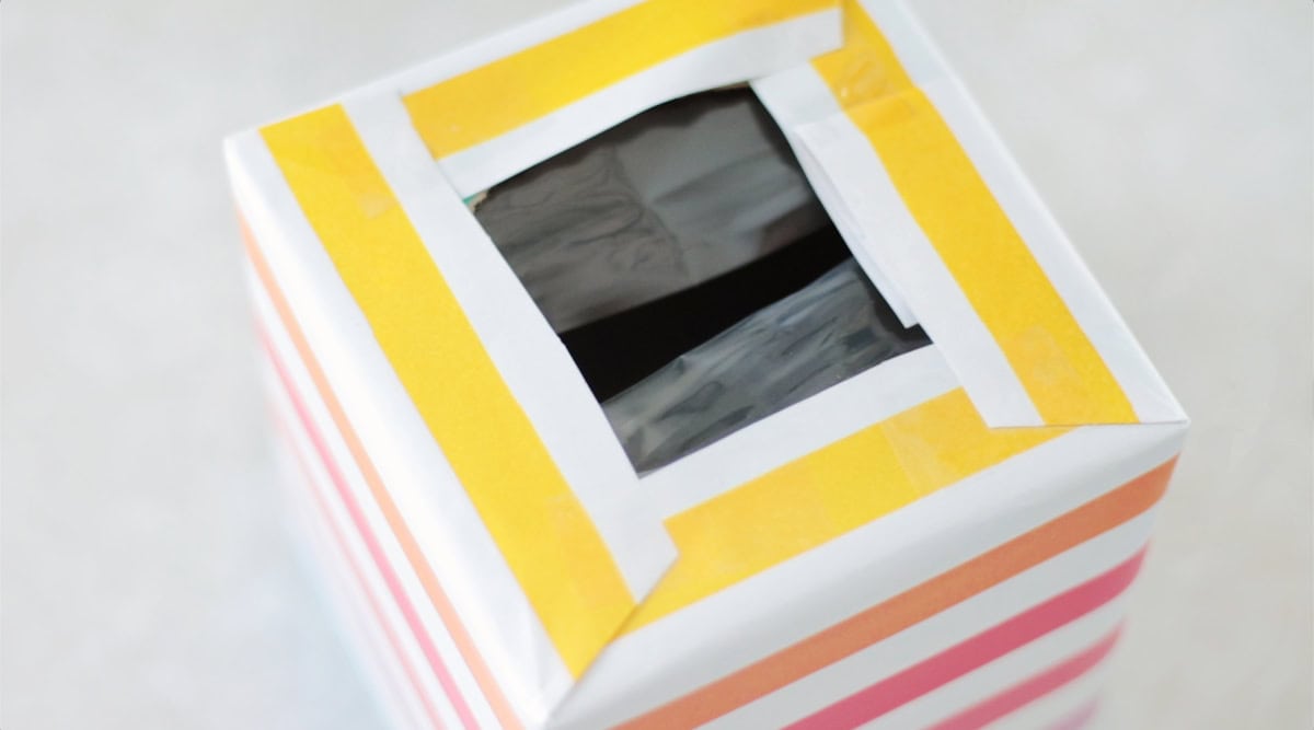 Tissue box wrapped in gift wrap with hole on the top.