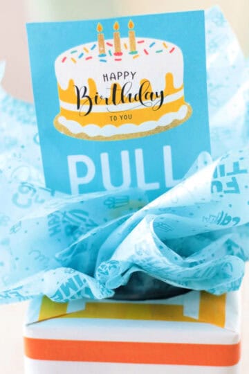 tissue box wrapped in gift wrap with tissue paper and a tag