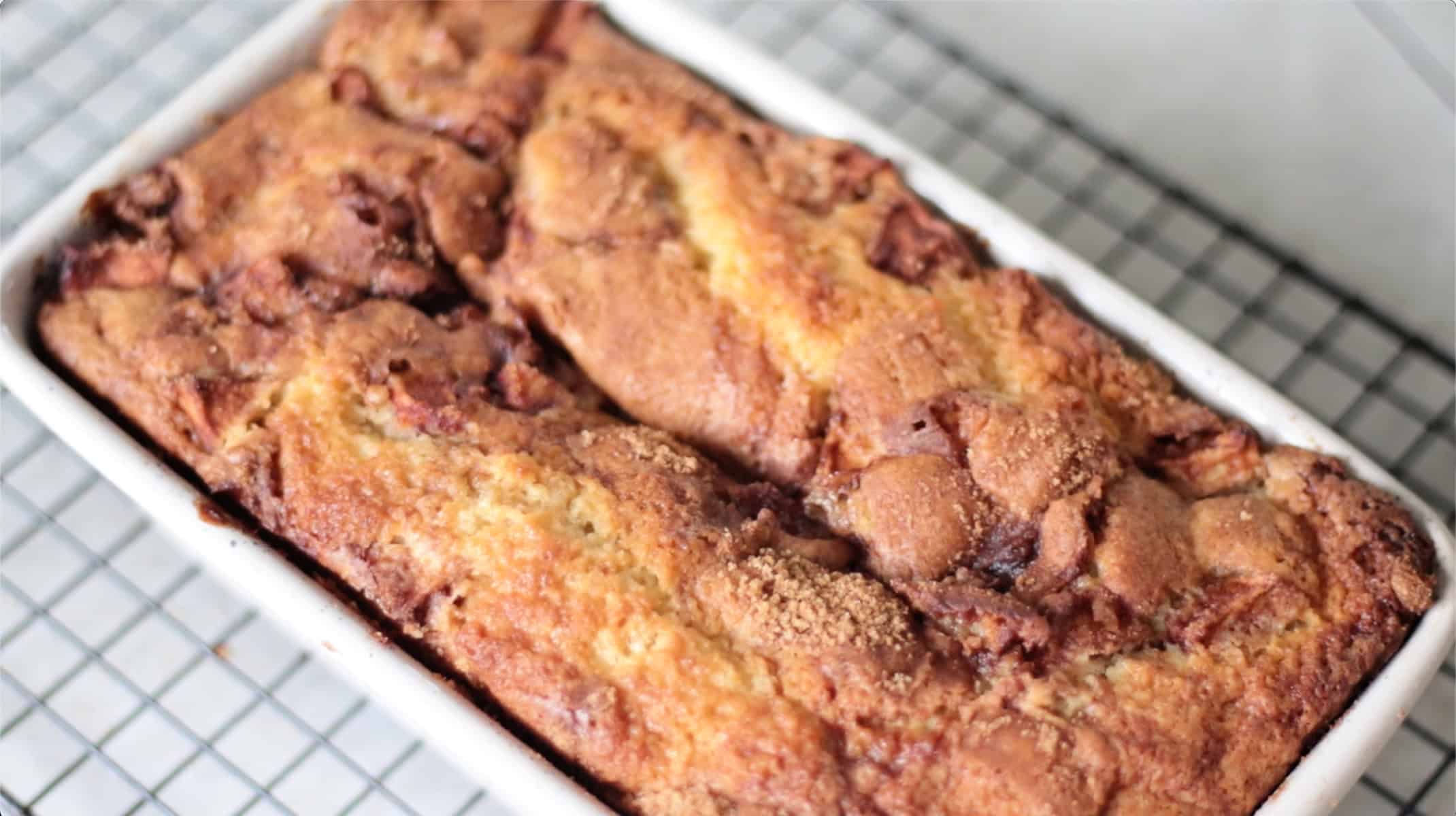 Apple fritter bread in pan, cooling on rack.