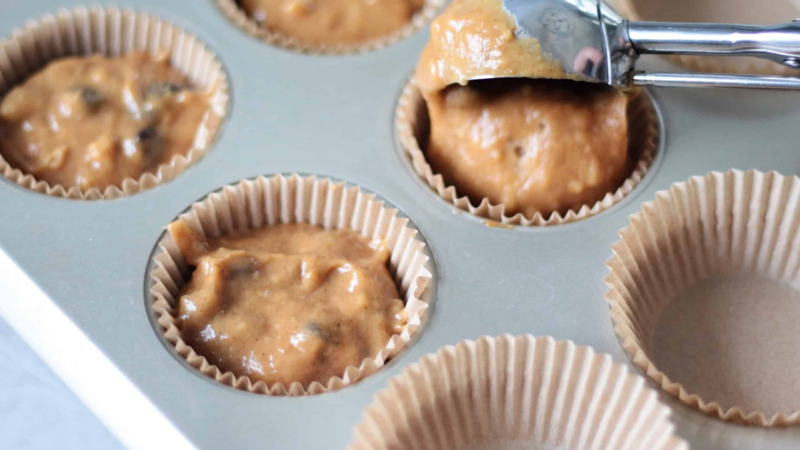 Pumpkin batter scooped into muffin pan with liners.