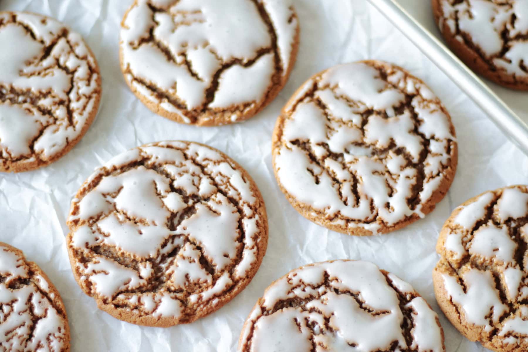 Iced molasses cookies on parchment paper.