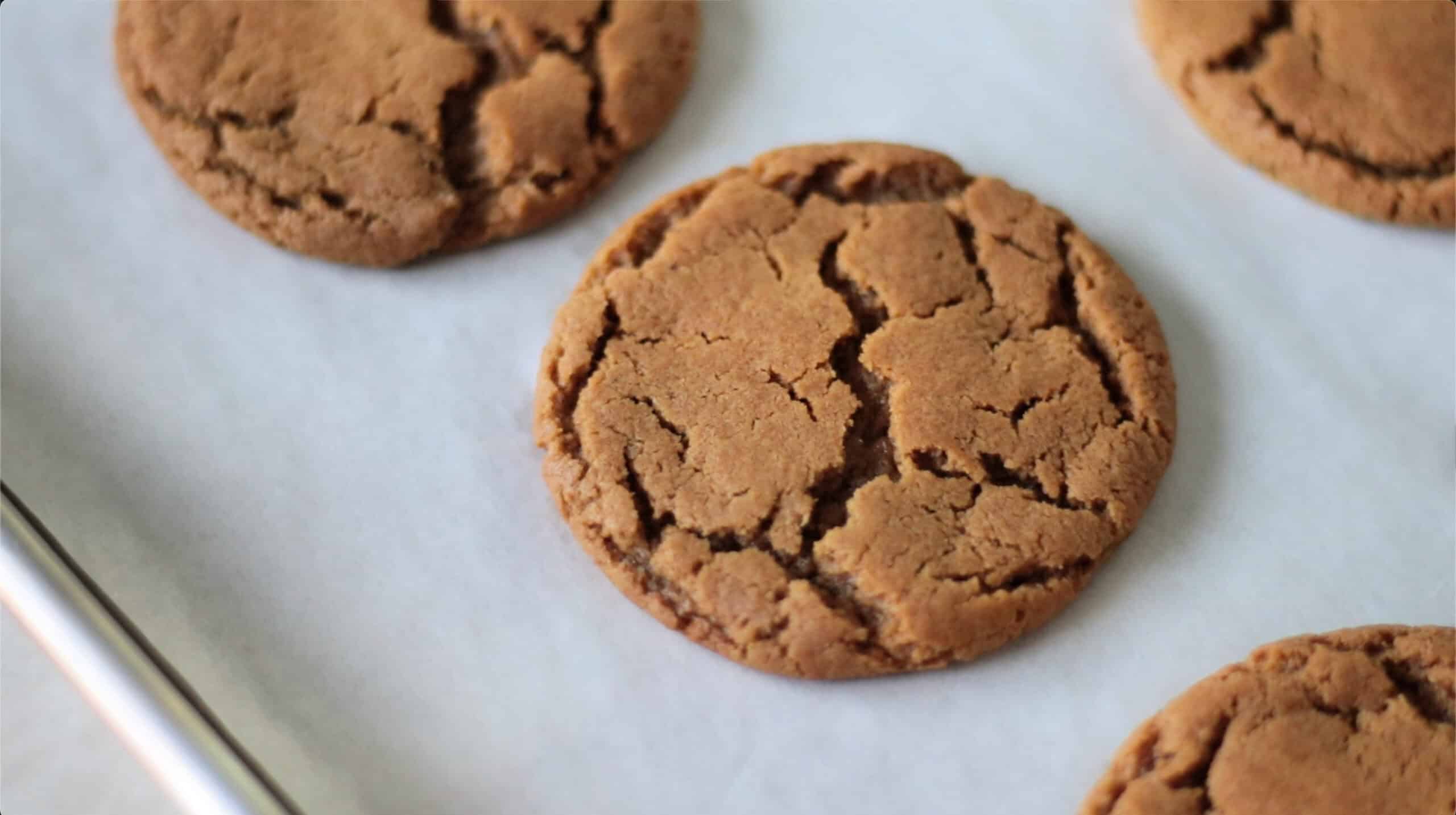 Molasses cookies on parchment-paper lined baking sheet.