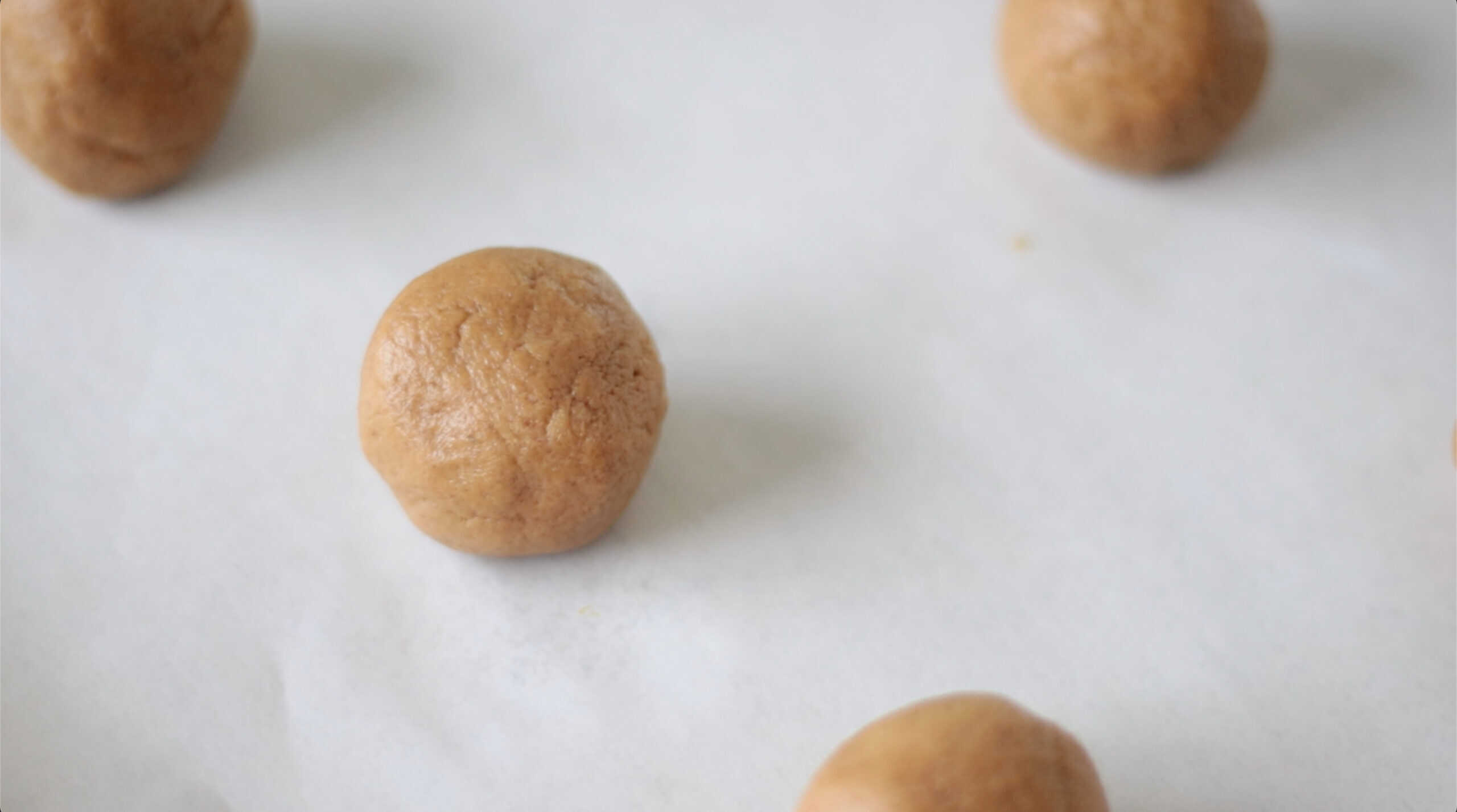 Rolls of molasses cookie dough balls on baking sheet.