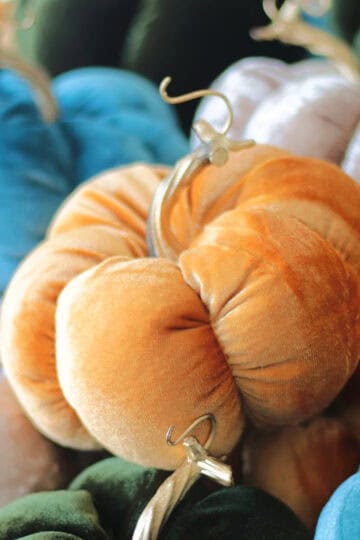 Orange velvet pumpkin stacked on other pumpkins.