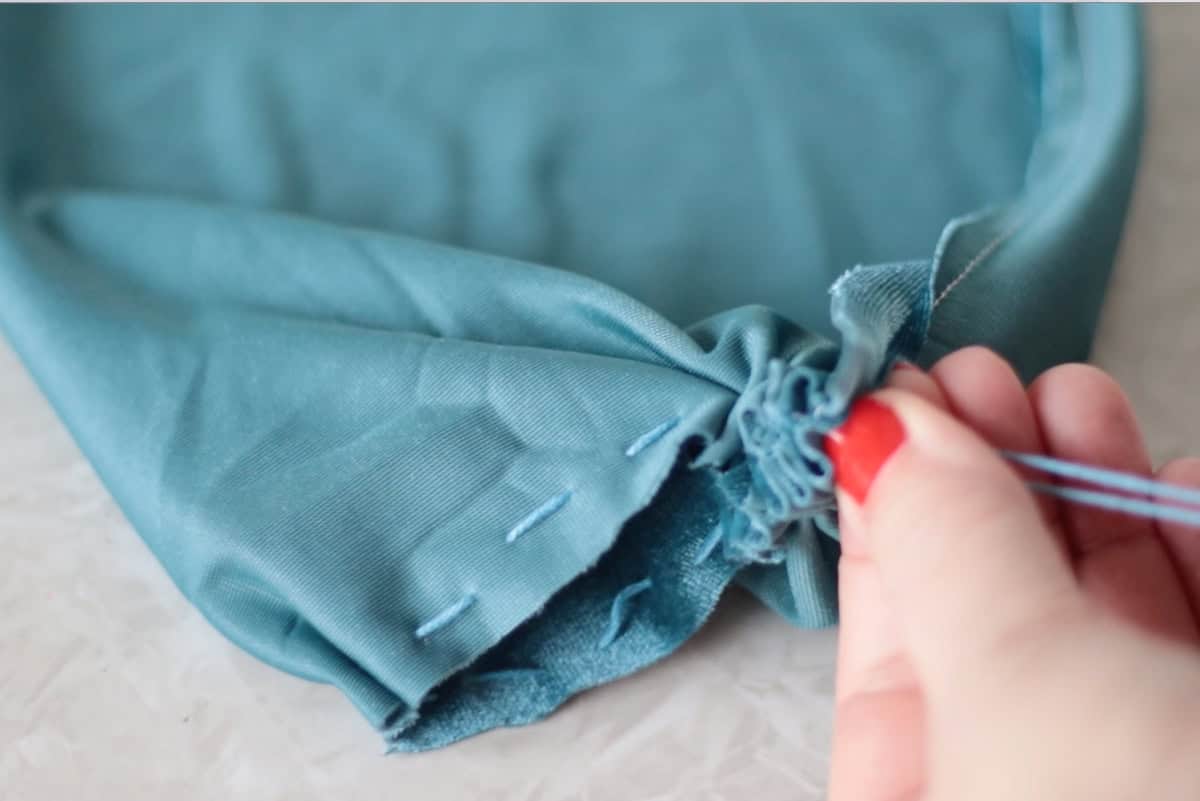 Hand pulling gathering strings on fabric.