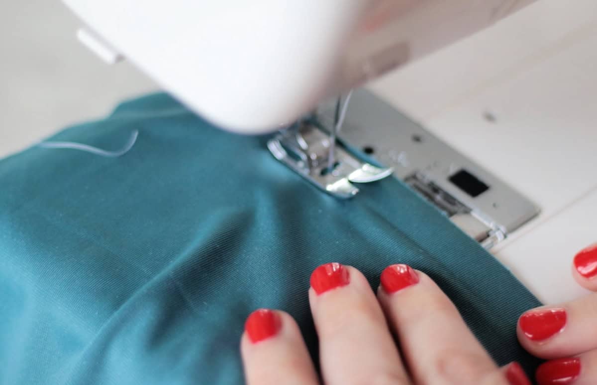 Sewing machine sewing a side seam on blue velvet fabric.