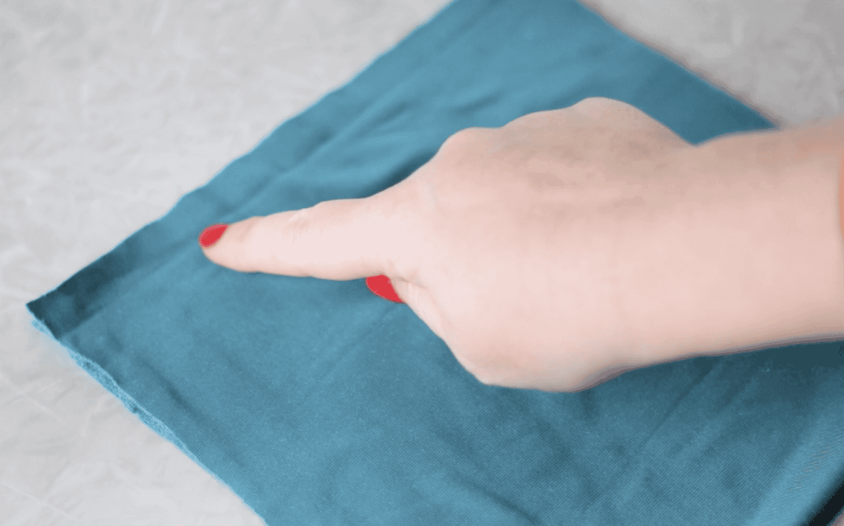 Velvet fabric folded in half with hand pointing at the top.