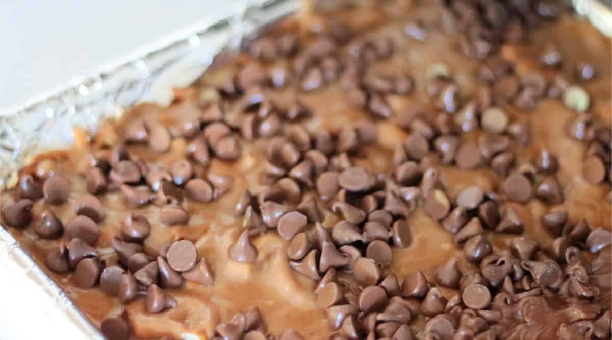 Chocolate chips sprinkled over pan of hot toffee.