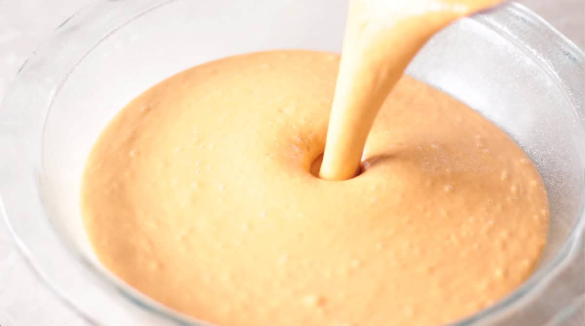 Pumpkin pie filling poured into glass pie pan.