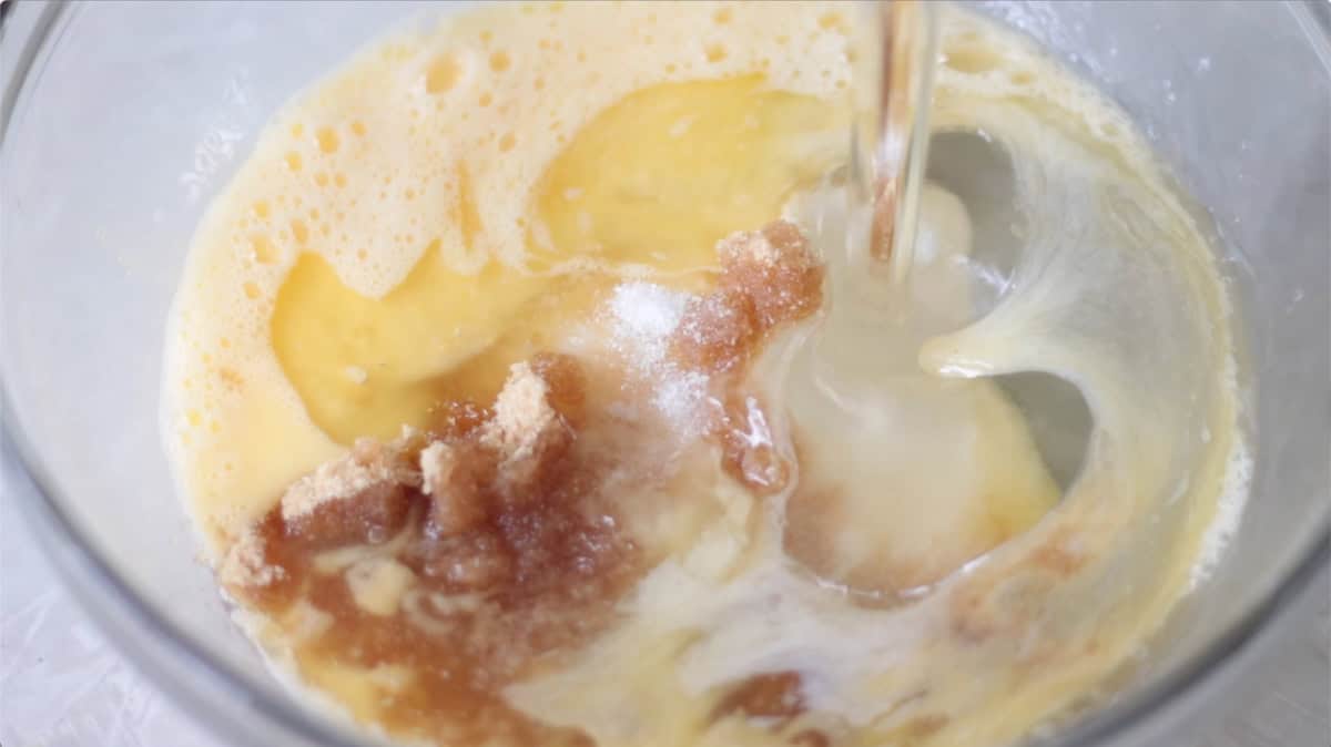 Glass mixing bowl with eggs, corn syrup, sugar, salt.