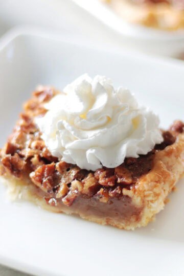 Slice of pecan slab pie on a white plate.
