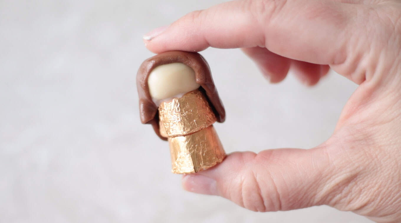 Hand holding a Mary candy figure made from Tootsie Rolls and Rolos.
