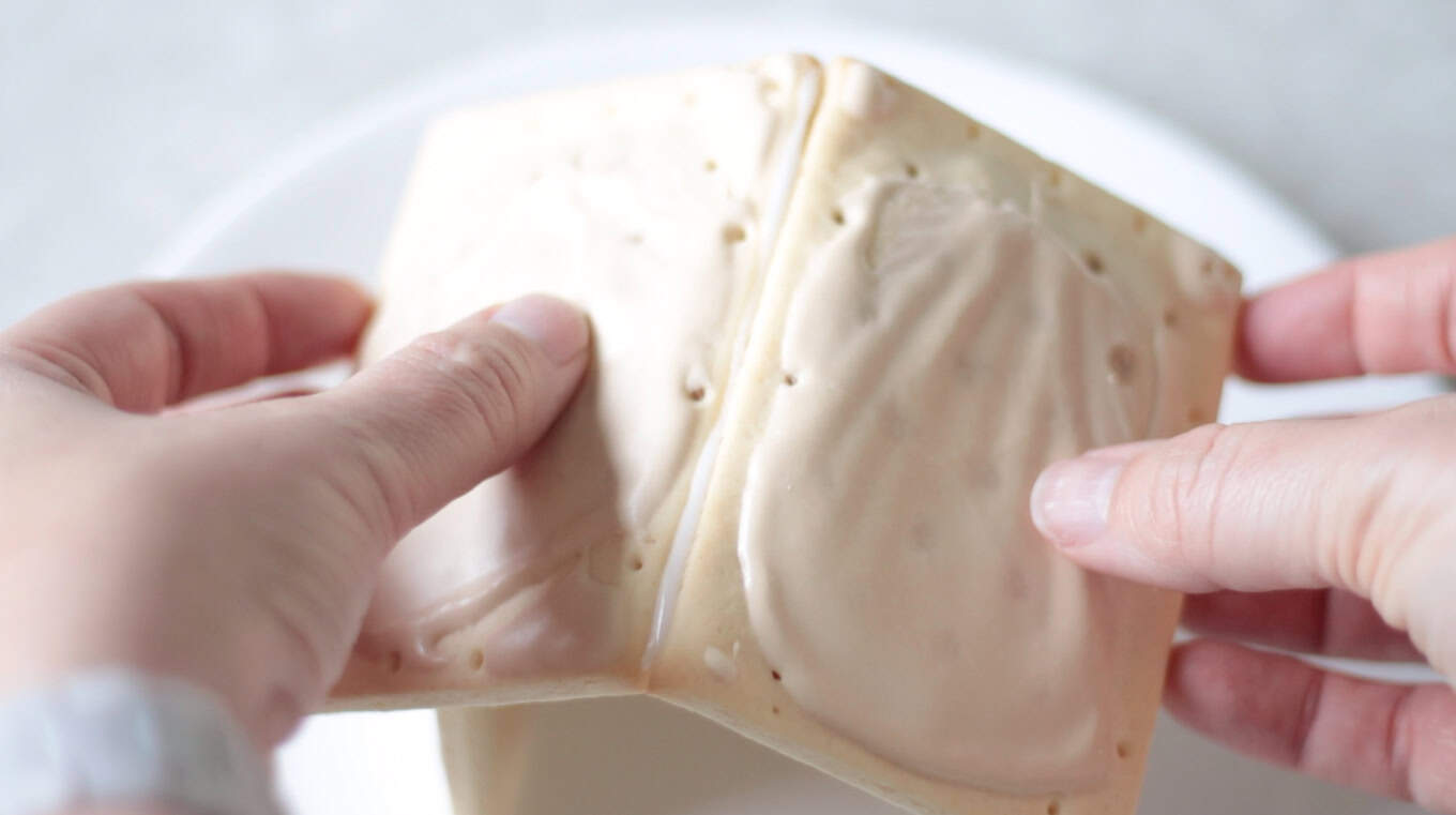 Hands holding two pop tarts in place for nativity roof.