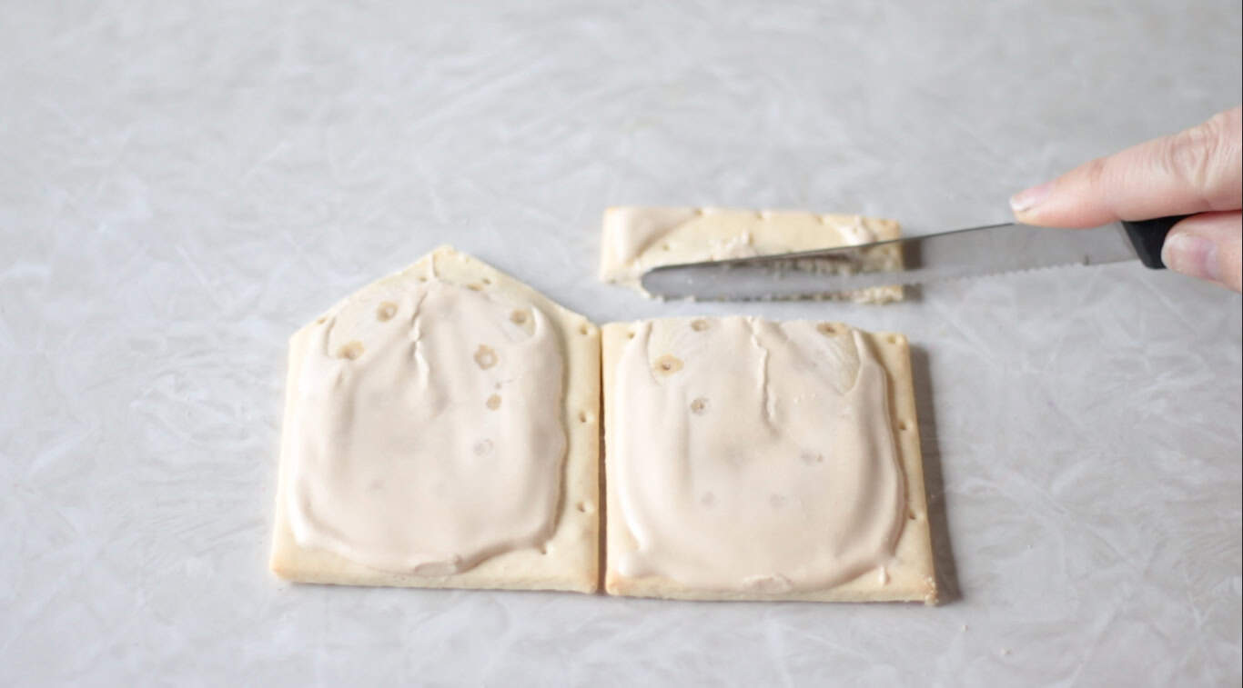 Two pop tarts and knife trimming a piece off of one.