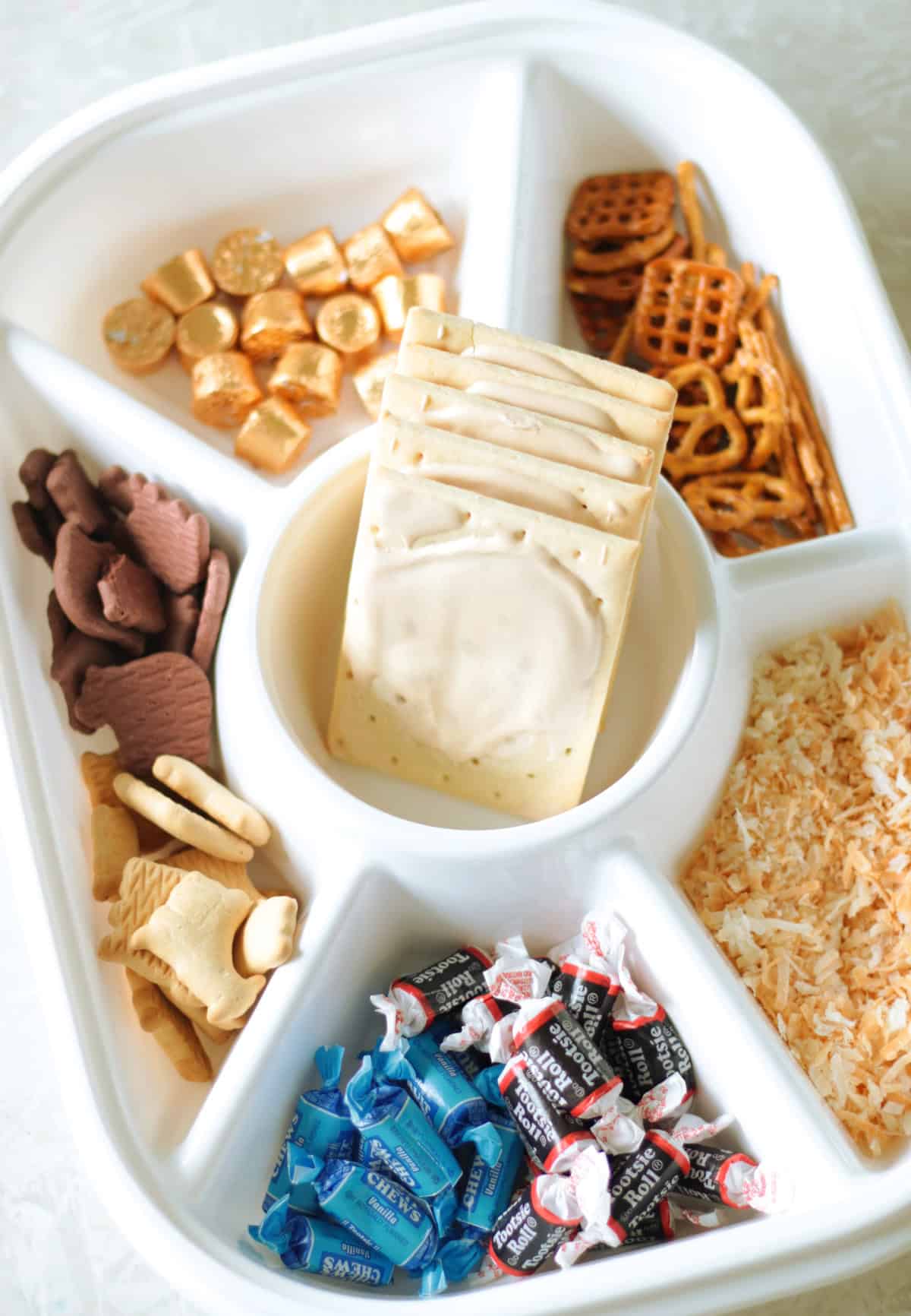 Divided serving tray with pretzels, Rolos, animal crackers, Tootsie Rolls, toasted coconut and pop tarts.