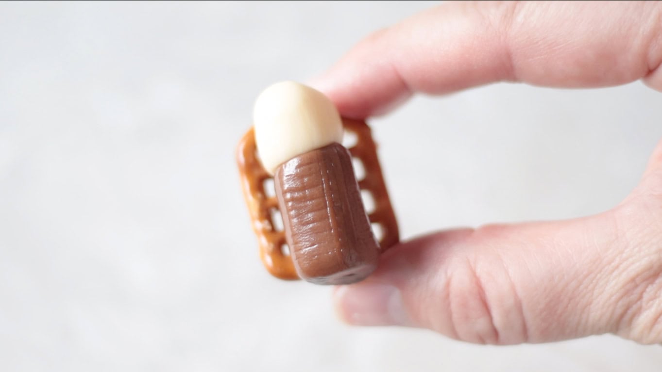 Hand holding a Baby Jesus made from tootsie rolls and a pretzel.