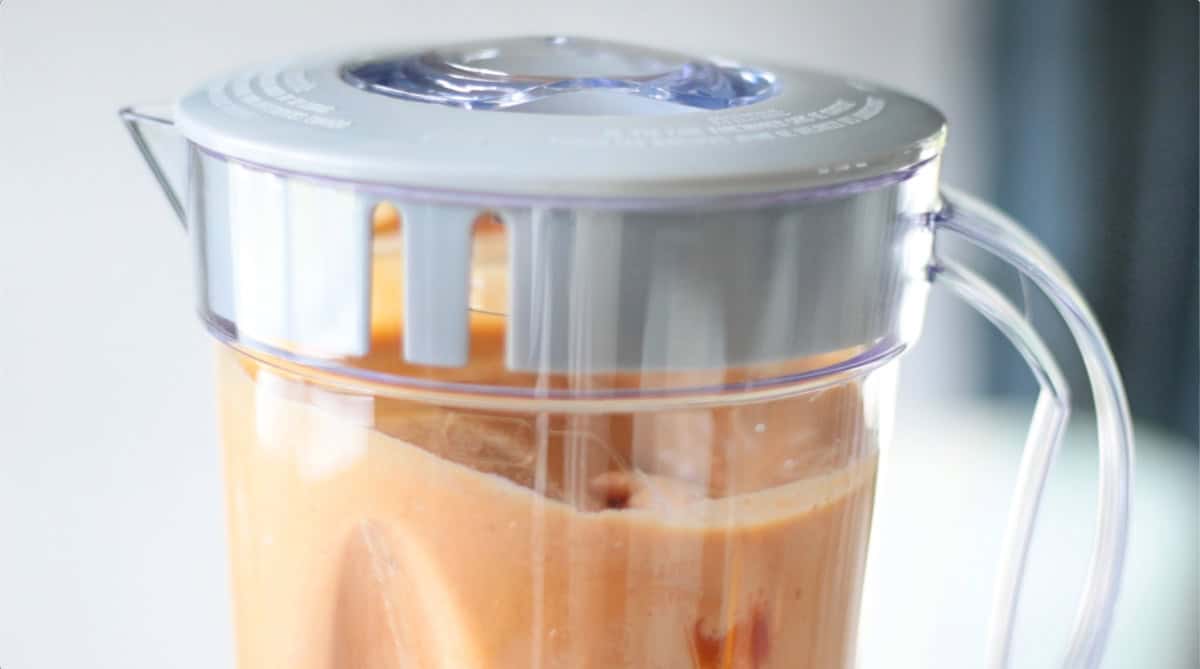 Blender with lid blending pumpkin pie filling.