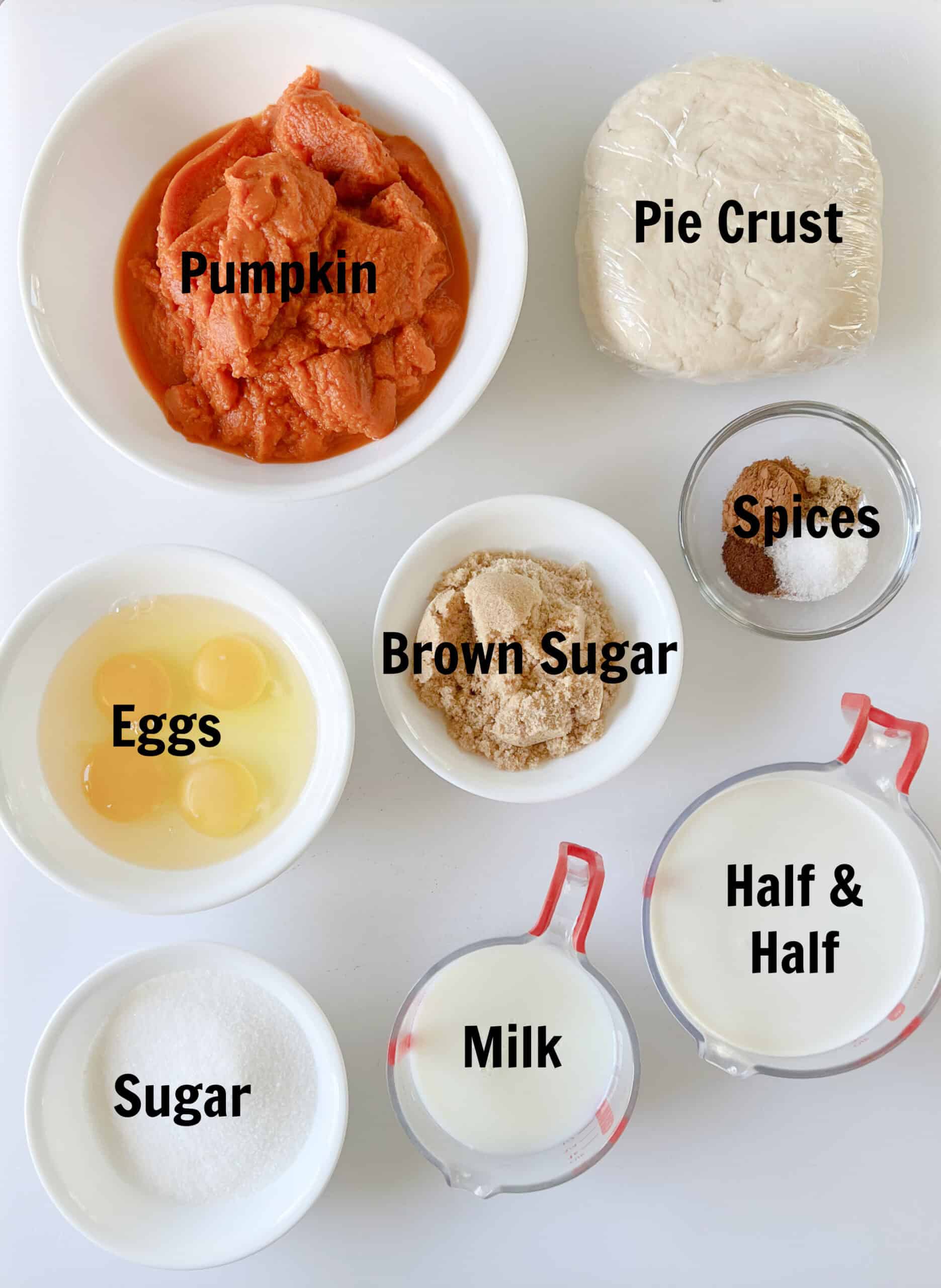Bowls of pumpkin puree, eggs, brown sugar, sugar, spices, sugar, milk, half and half and pie crust.