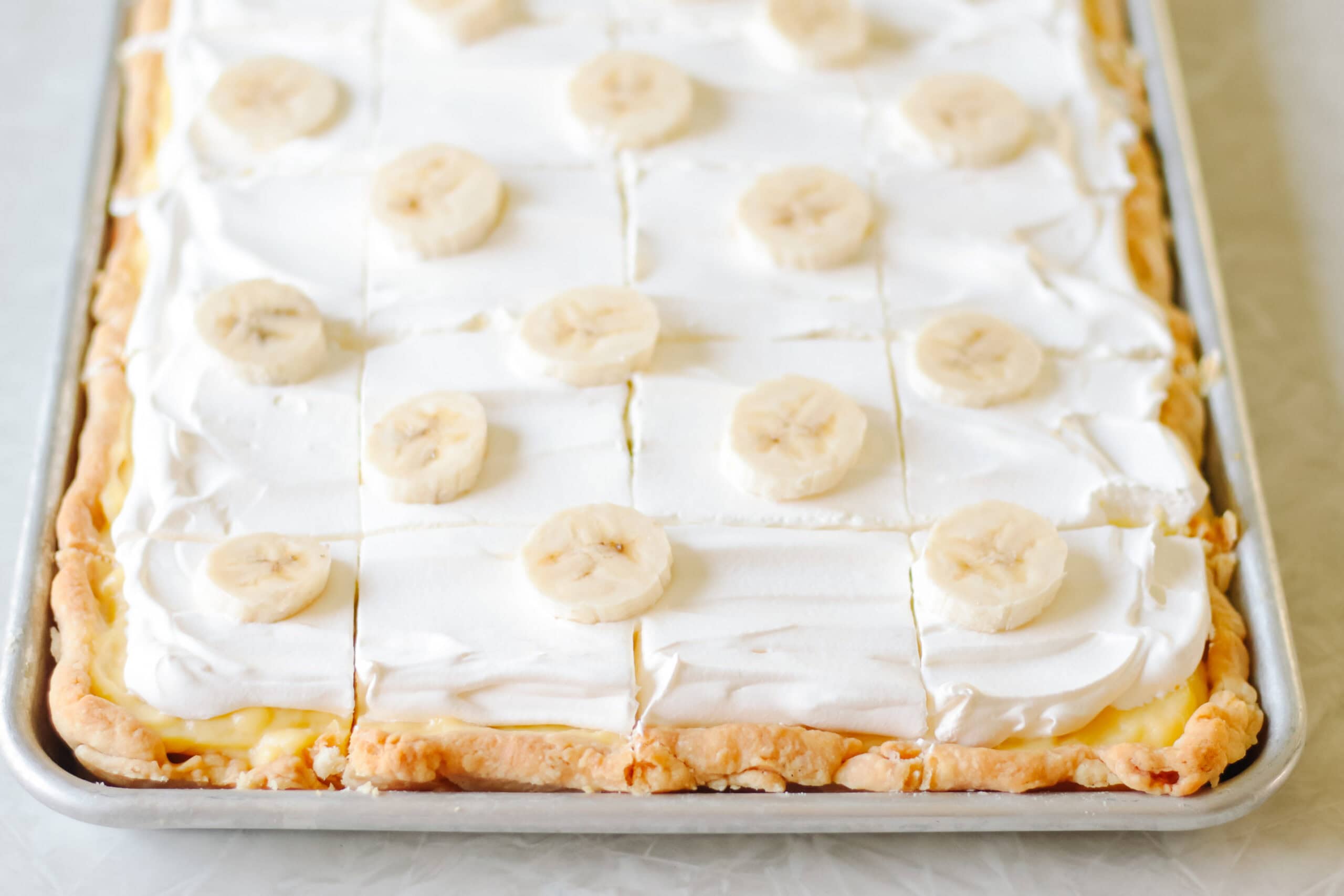 Banana cream slab pie sliced in pan.
