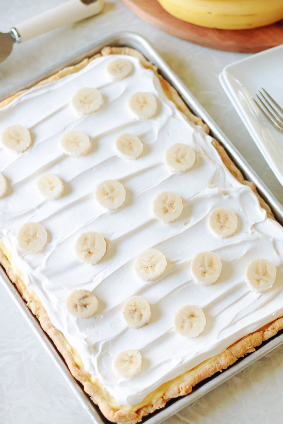 Sheet pan banana cream pie with whipped cream and sliced bananas.