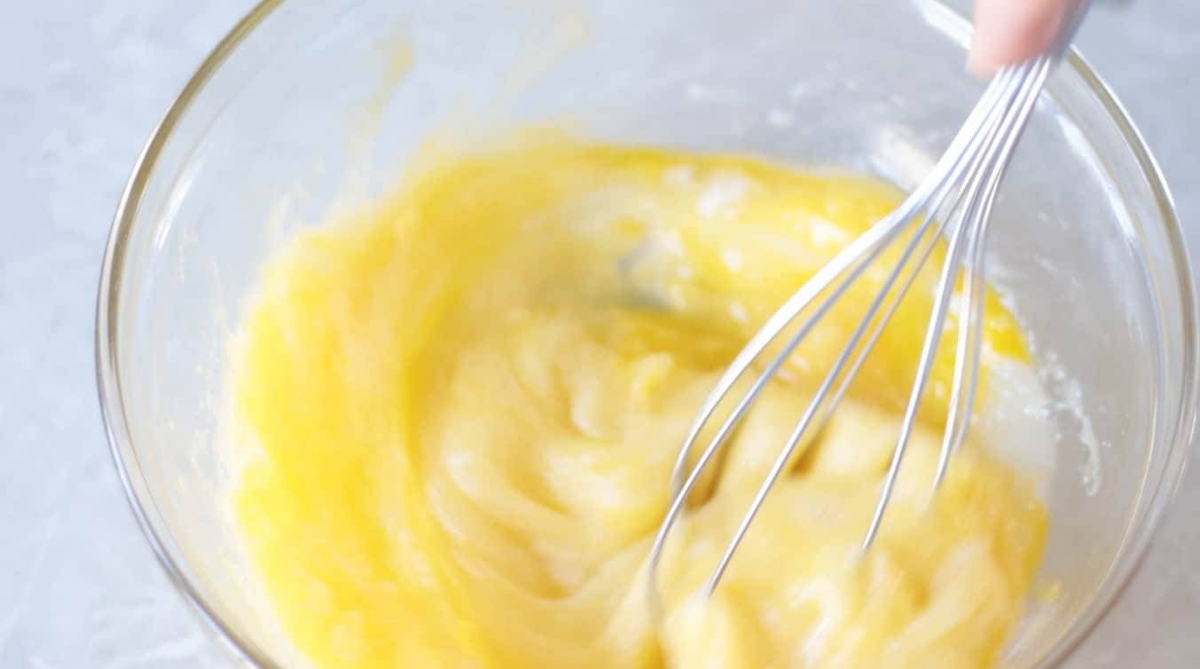 Glass bowl with eggs and sugar whisked together.