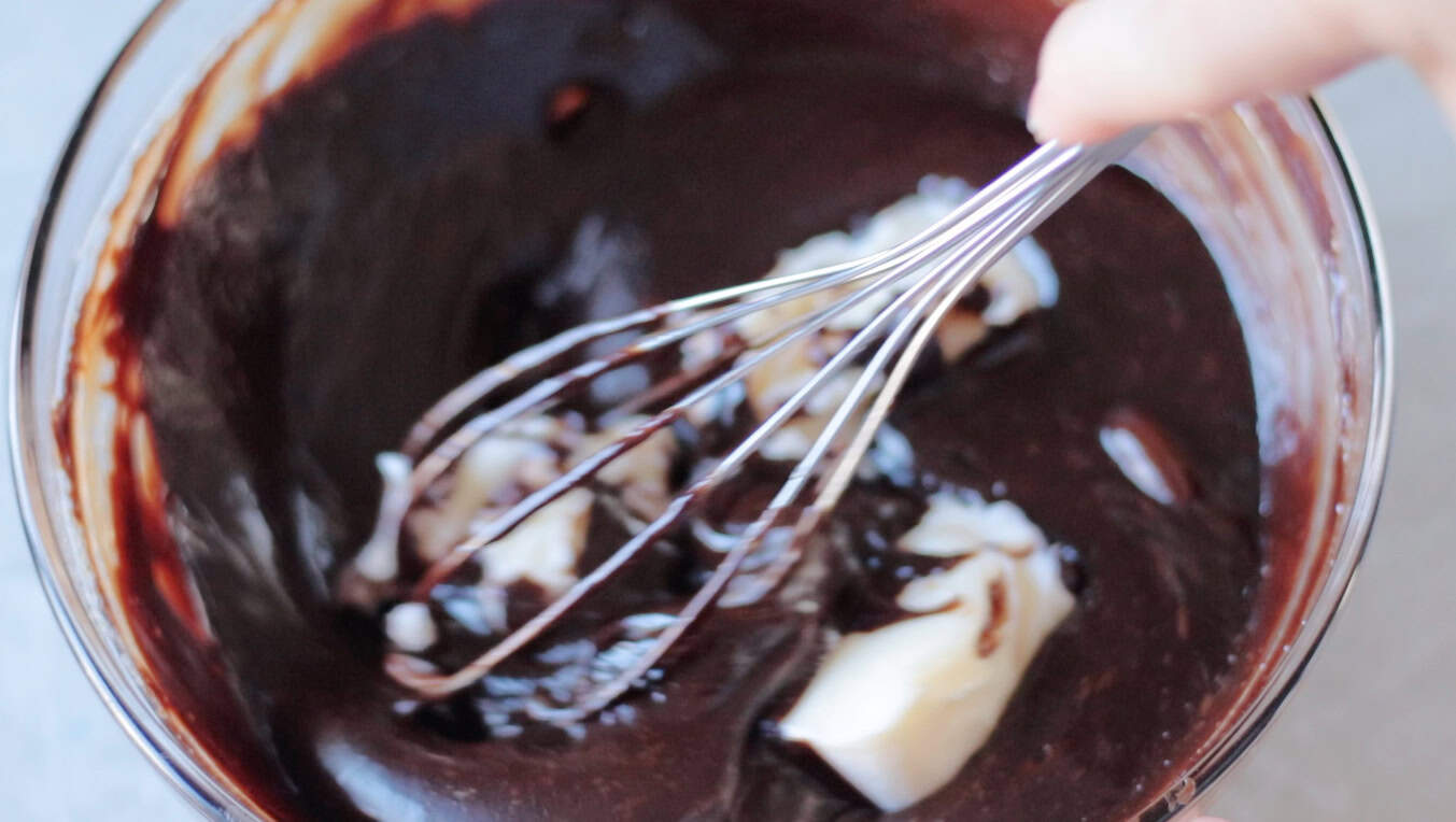 Whisk mixing butter into chocolate mixture.