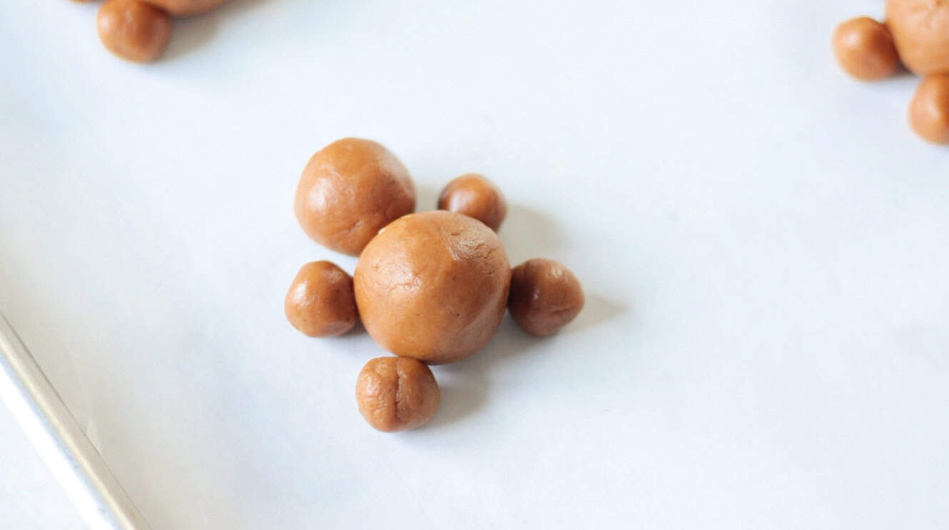 Balls of gingerbread cookie dough pressed into gingerbread man shape.
