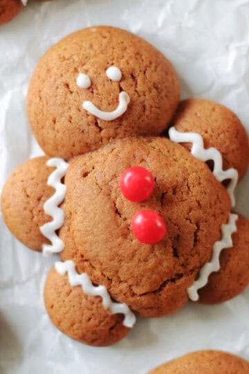 Chubby gingerbread man cookie with white icing and red candy buttons.