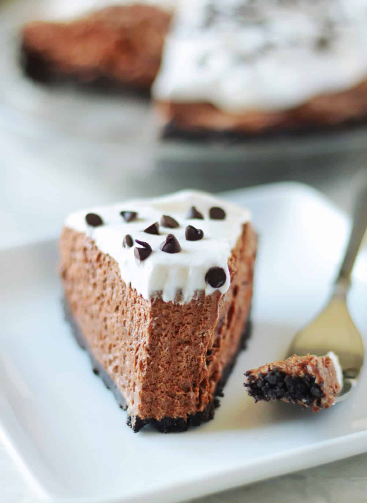Slice of French silk pie on a white plate with a forkful of pie next to it.