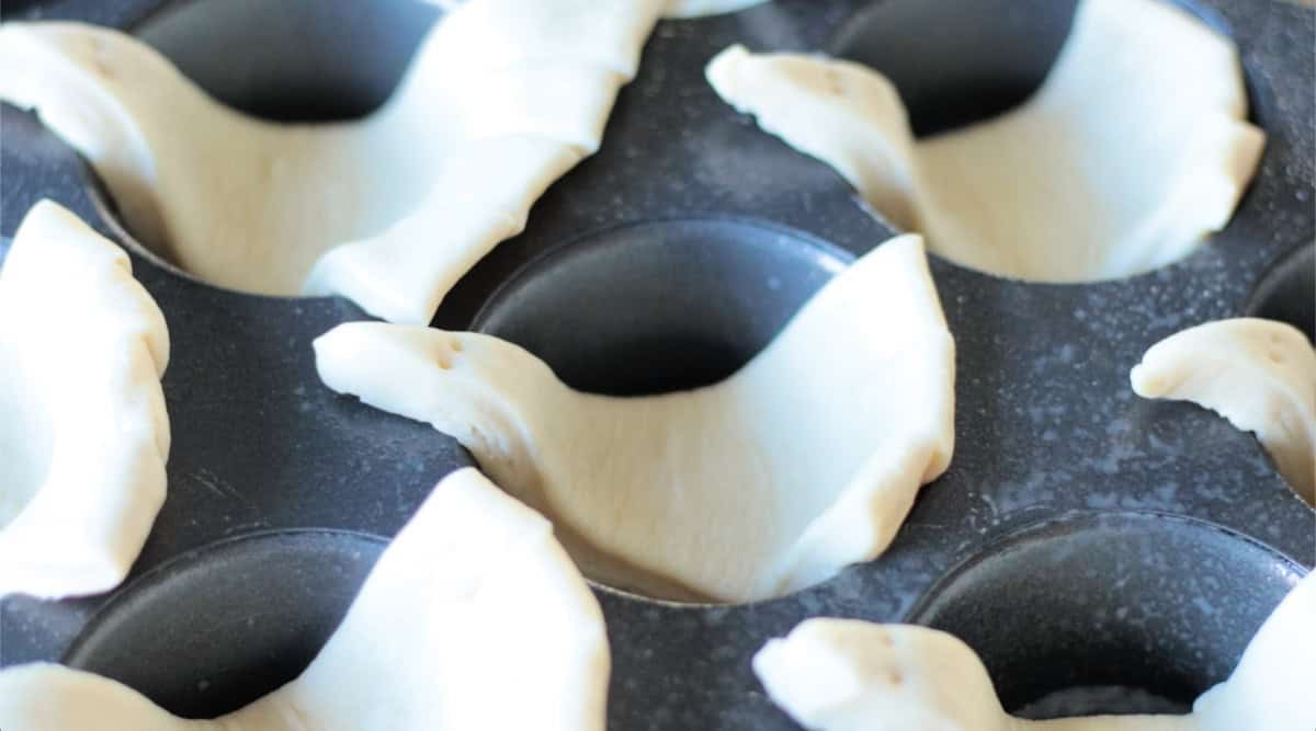 Muffin pan with unbaked turkey rolls.