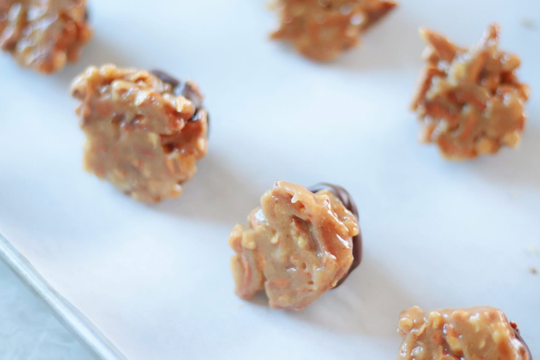 Peanut butter clusters positioned on their side on baking sheet.