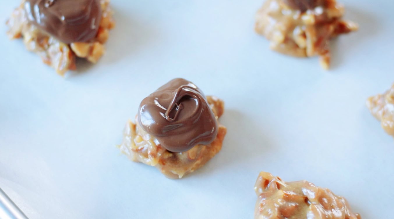Chocolate spooned on top of peanut butter pretzel clusters.
