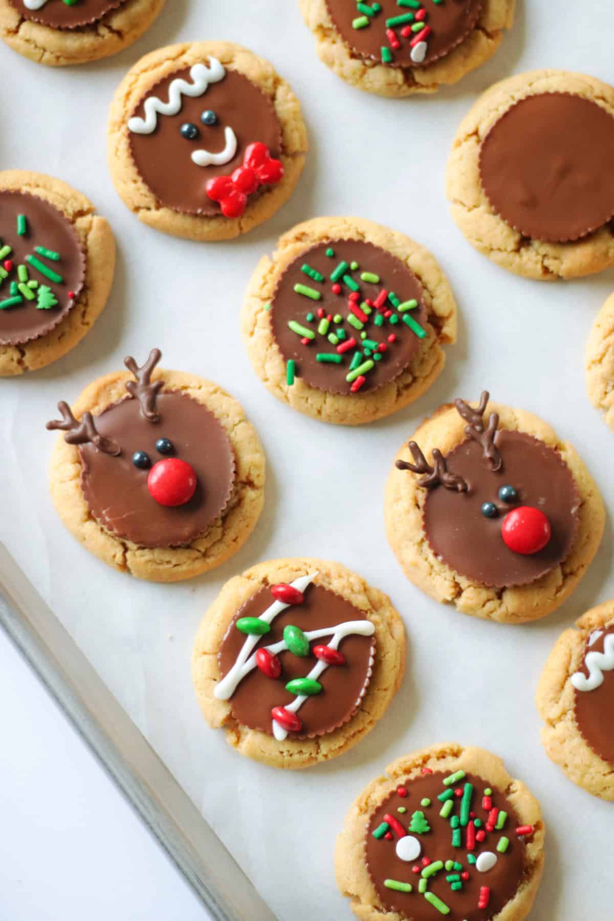Baking sheet of peanut butter cookies decorated with sprinkles and holiday designs.