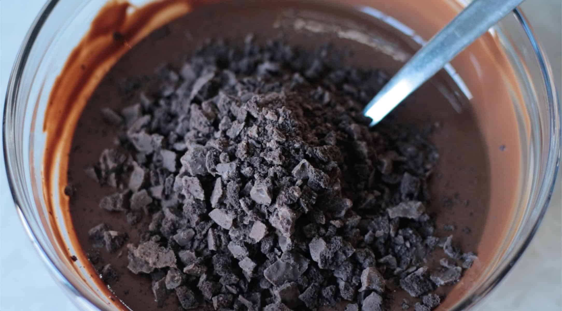 Glass bowl of chocolate and chopped mint cookies with spoon.