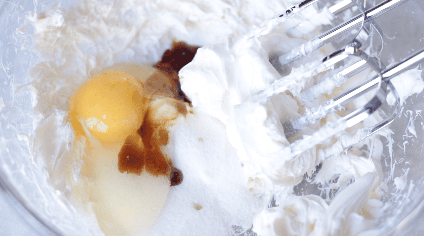 Bowl of cream cheese, an egg, sugar and vanilla.