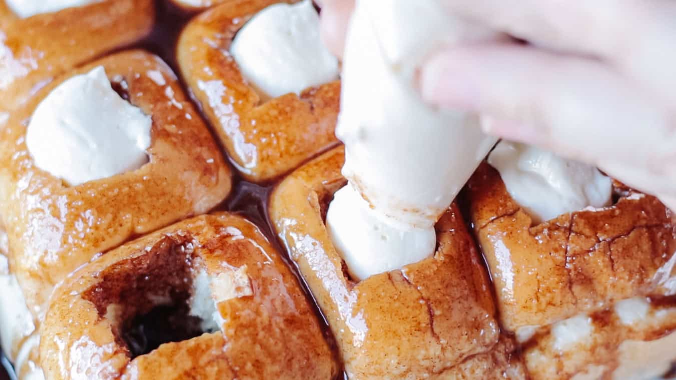 Piping bag full of cheesecake filling piped into rolls.