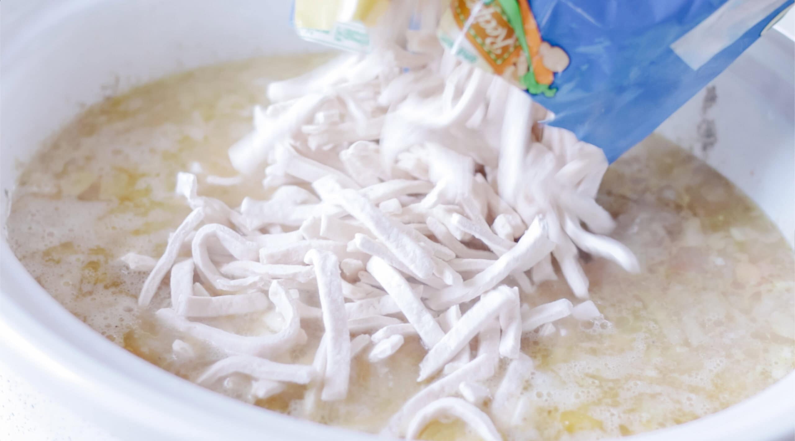 A bag of frozen egg noodles in a slow cooker.