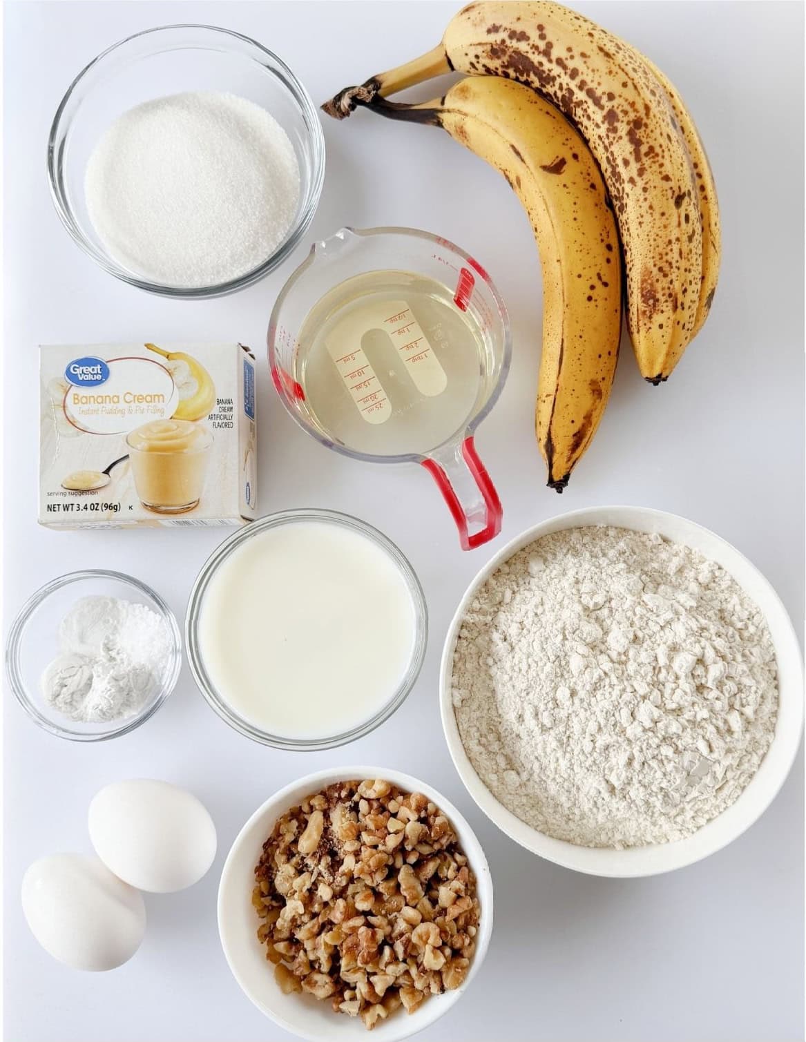 Bowls of oil, sugar, milk, flour, walnuts, baking soda, baking powder and salt, two eggs, box of vanilla pudding and 3 ripe bananas.