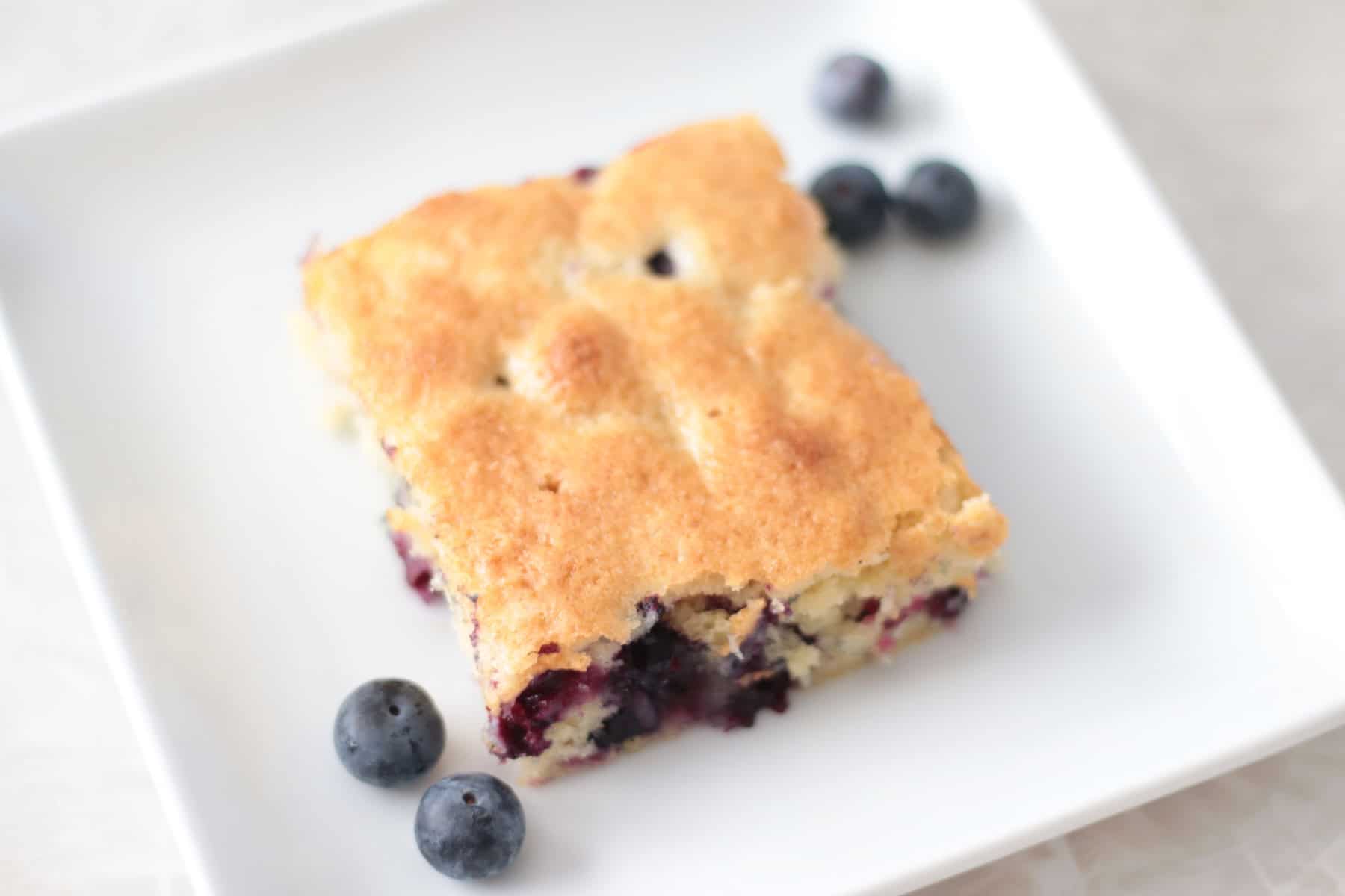 Slice of blueberry cake on white plate.