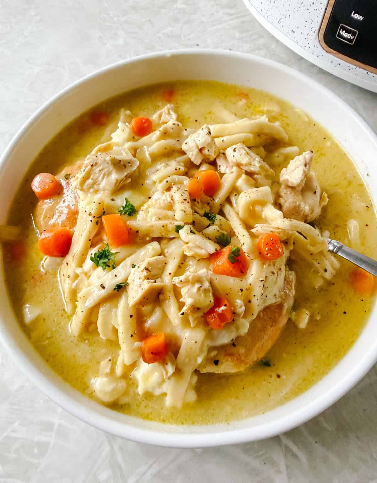 White bowl of chicken and noodles.