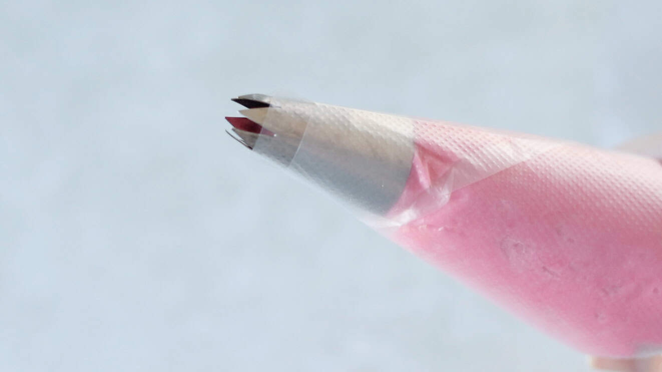 Large open star frosting tip on frosting bag filled with pink cookie dough.