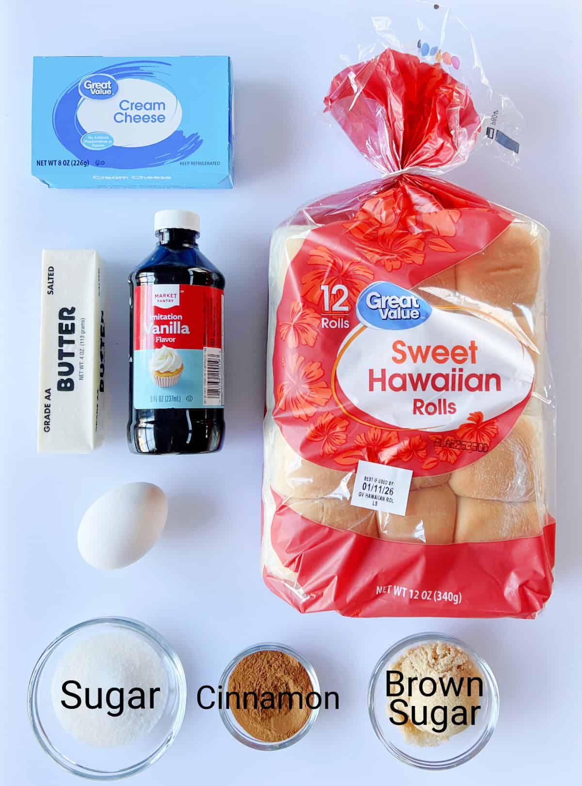 Box of cream cheese, stick of butter, bottle of vanilla, egg, bowls of sugar, brown sugar and cinnamon and bag of Hawaiian rolls.