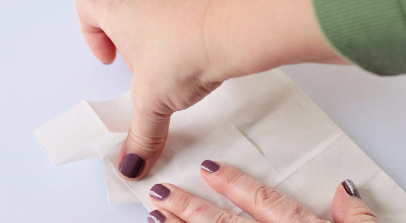 Fingers folding bag sides to form sleeves.